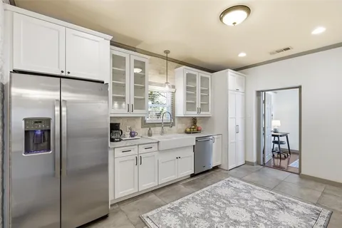 a kitchen with stainless steel appliances granite countertop a refrigerator a sink and white cabinets