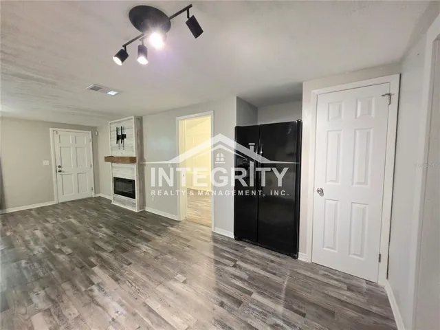 a kitchen with granite countertop a refrigerator a sink dishwasher a stove and white cabinets with wooden floor