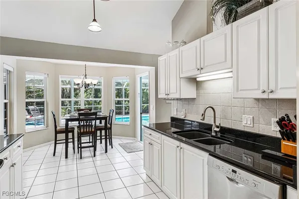 a kitchen with granite countertop a sink a stove and white cabinets