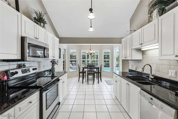 a kitchen with granite countertop a sink a counter top space appliances and cabinets
