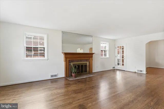 an empty room with wooden floor fireplace and windows