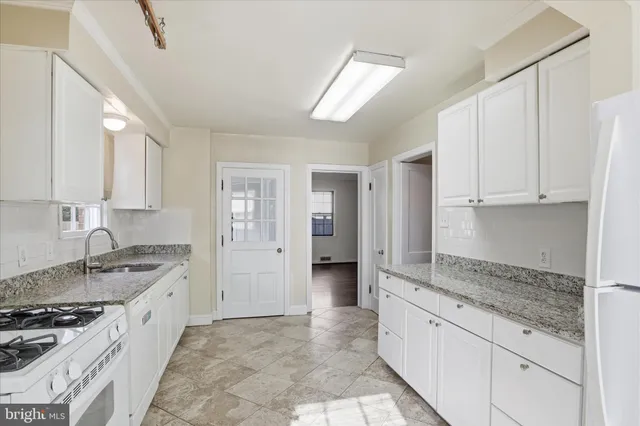 a kitchen with granite countertop a sink stove and cabinets