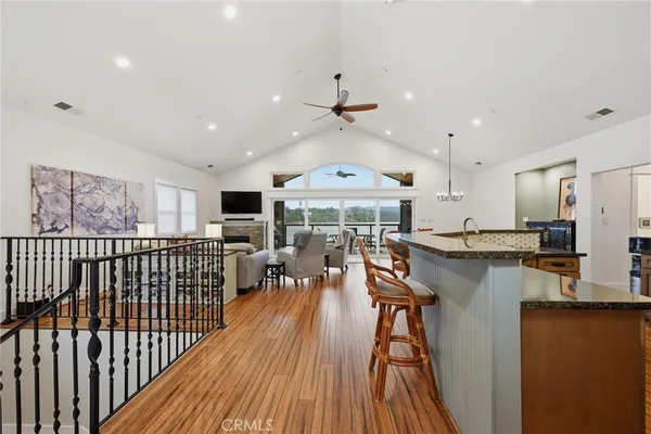 a kitchen with stainless steel appliances granite countertop a stove top oven a sink dishwasher a dining table and chairs with wooden floor