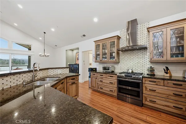 a kitchen with stainless steel appliances granite countertop a sink and wooden floor