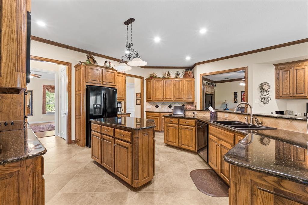 10072 Bluffview Circle Pilot Point, TX 76258 - Photo 17 of 38 Kitchen featuring brown cabinets, decorative backsplash, a center island, dark stone countertops, and crown molding
