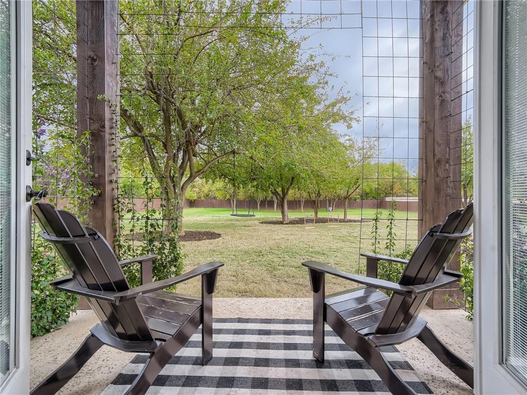 132 Huerta Road Florence, TX 76527 - Photo 33 of 40 Relax on the patio overlooking a verdant backyard with mature trees and ample space for recreation.