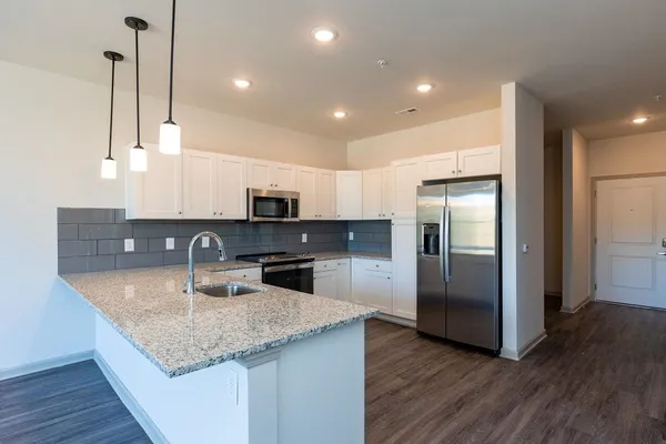 a kitchen with stainless steel appliances granite countertop a sink a refrigerator and microwave