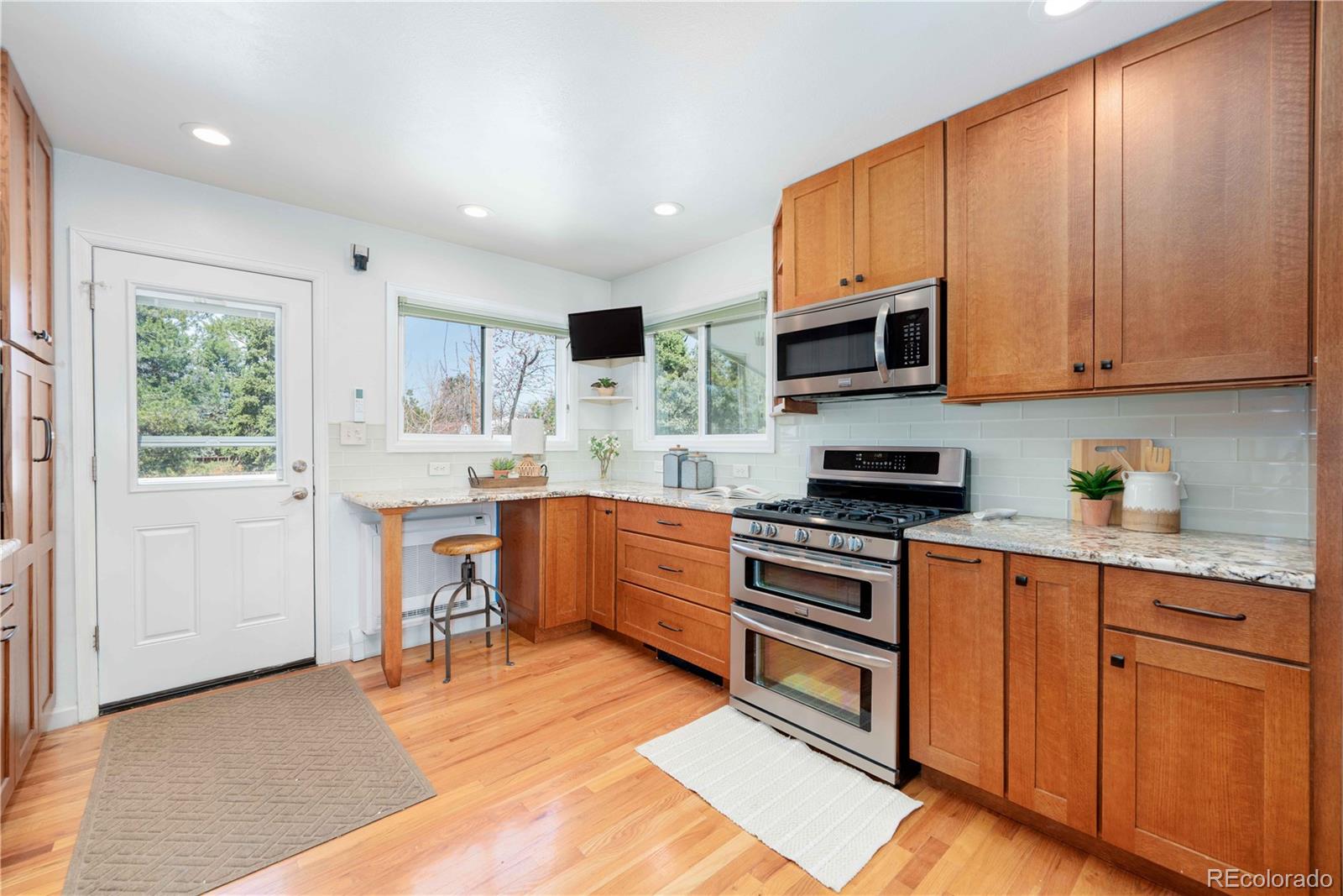 3815 East Easter Place Centennial, CO 80122 - Photo 6 of 35 a kitchen with stainless steel appliances granite countertop a stove top oven a sink dishwasher and a refrigerator with wooden floor
