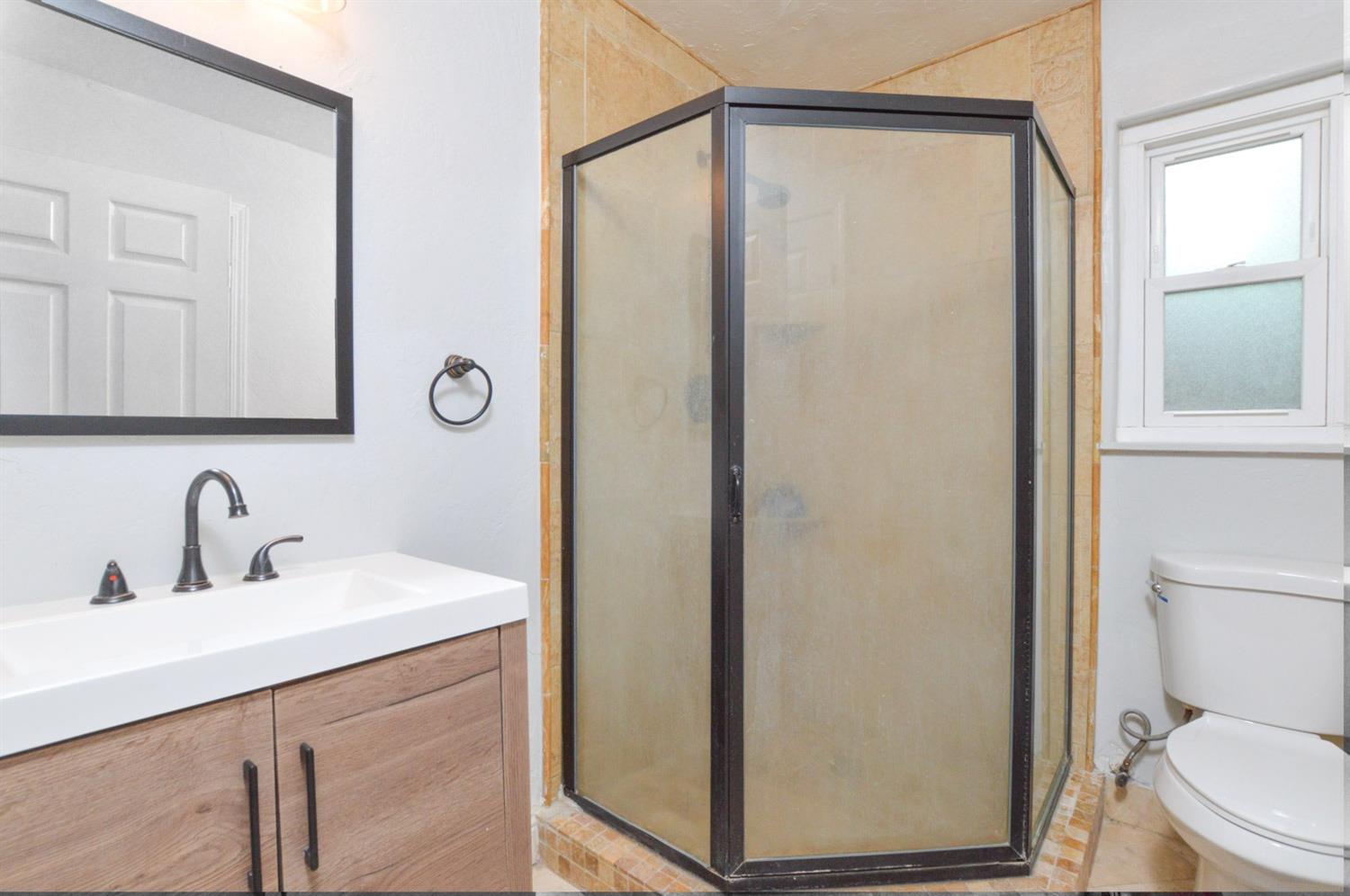 4613 West Andrews Fresno, CA 93722 - Photo 14 of 20 a bathroom with a sink a toilet a mirror and shower