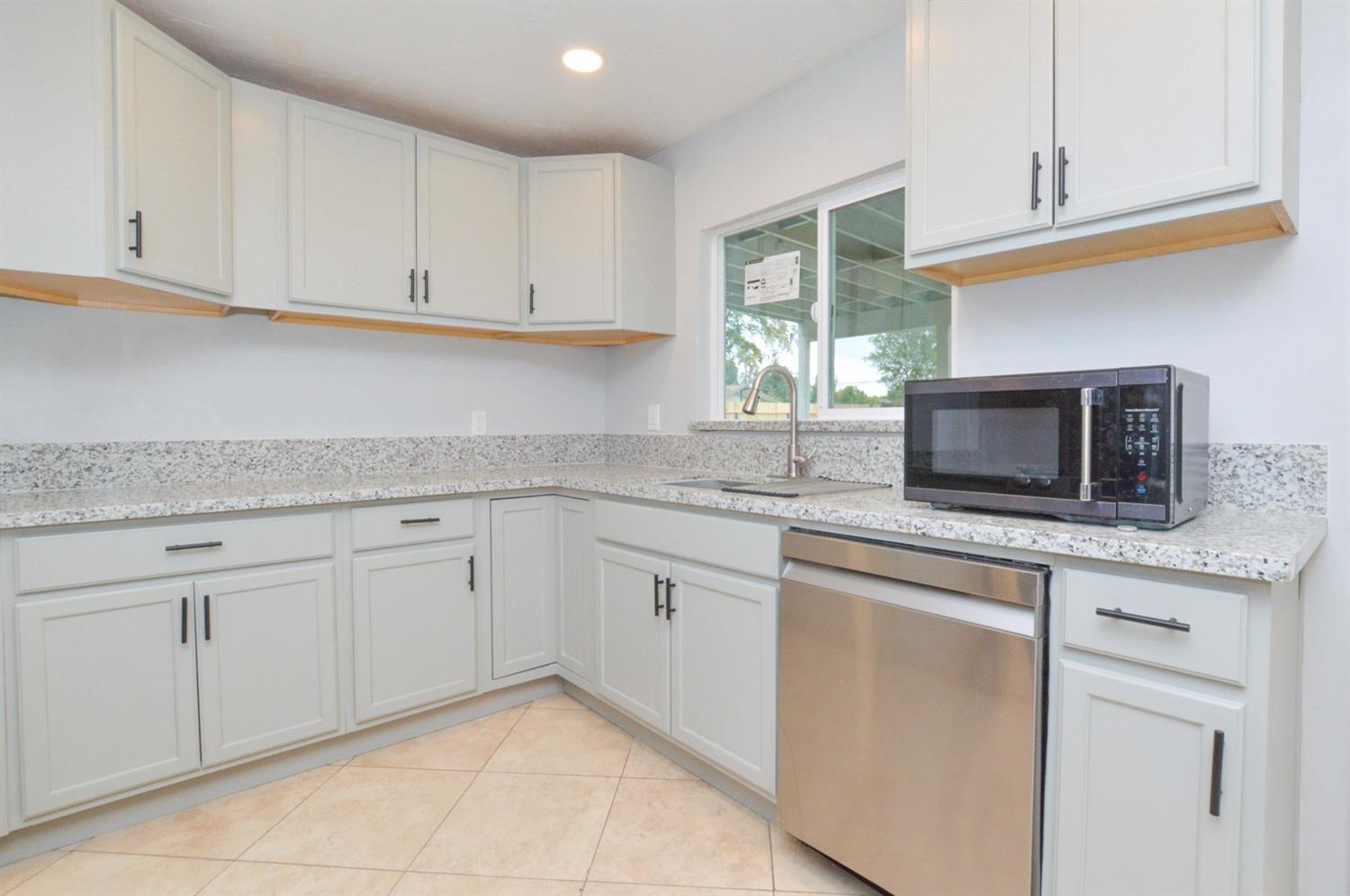 4613 West Andrews Fresno, CA 93722 - Photo 8 of 20 a kitchen with granite countertop white cabinets and stainless steel appliances