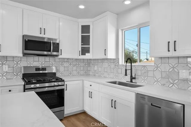 a kitchen with granite countertop white cabinets and black stainless steel appliances