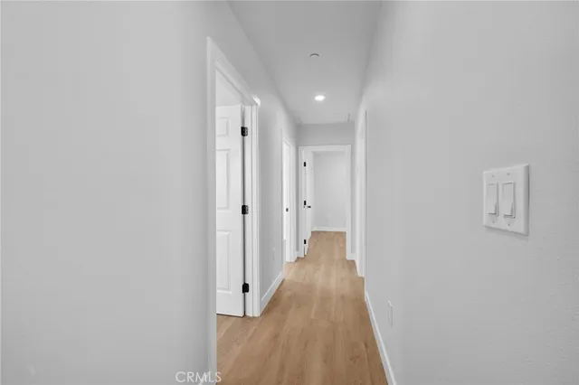 a hallway with wooden floor and a bathroom