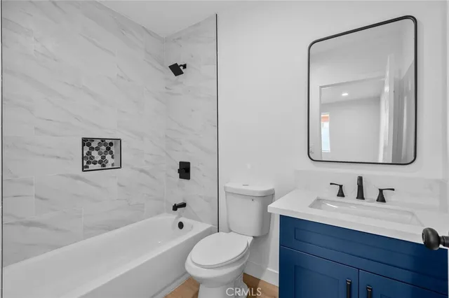 a bathroom with a toilet a sink a mirror a bathtub and vanity