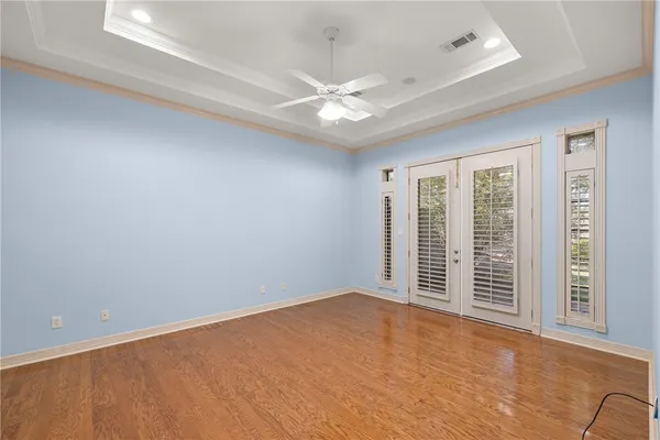 an empty room with wooden floor cabinet and windows