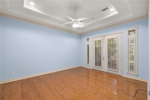 an empty room with wooden floor cabinet and windows