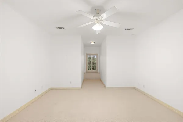 an empty room with a ceiling fan and a window