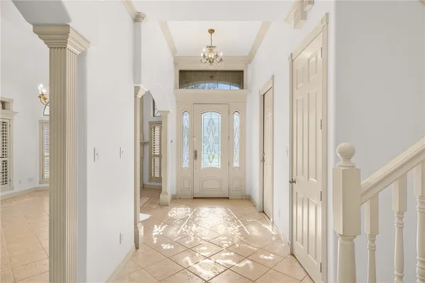 a view of a hallway with a dining area chandelier and front door