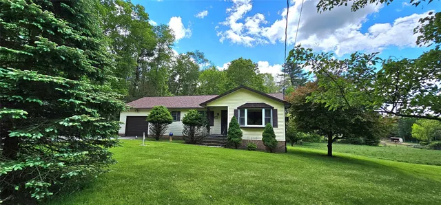 a front view of a house with a yard and trees