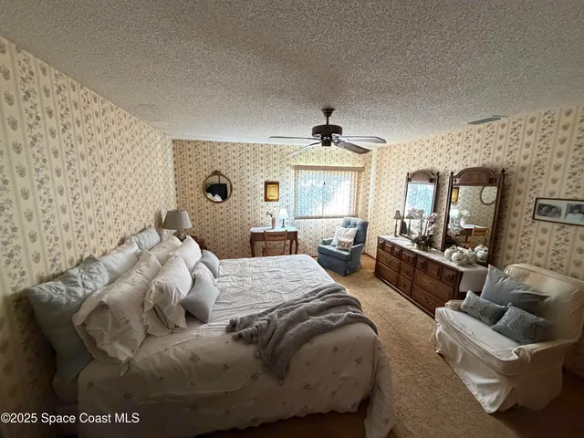 a bedroom with a bed couches and a flat tv screen