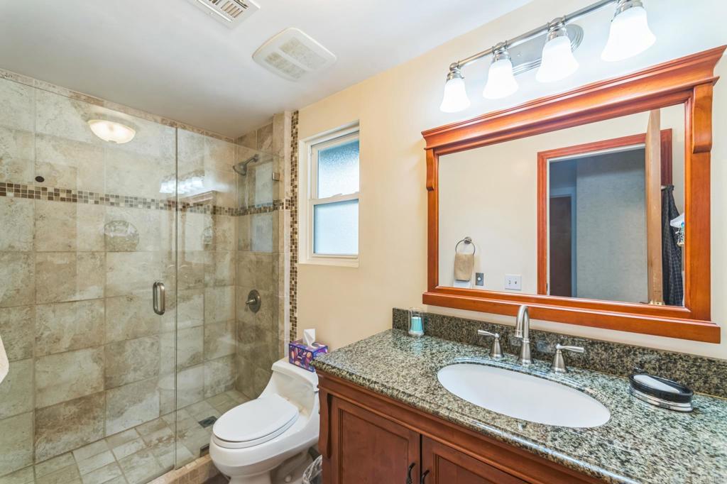 28969 Mountain Meadow Road Escondido, CA 92026 - Photo 23 of 25 a bathroom with a granite countertop sink a toilet a mirror and shower