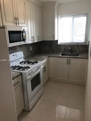 a kitchen with stainless steel appliances a stove a microwave a sink and cabinets