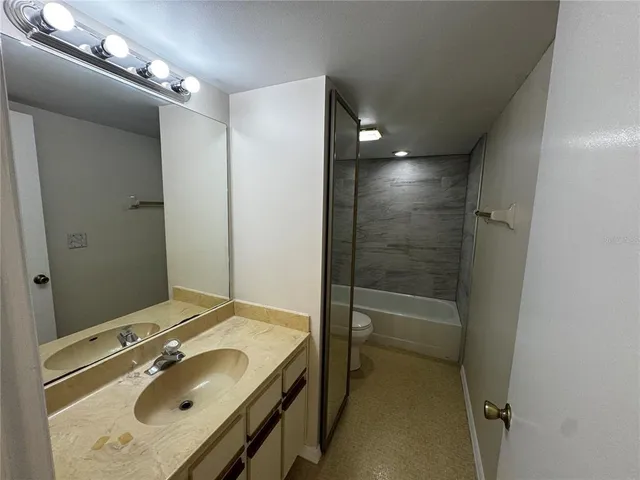 a bathroom with a sink a toilet a mirror and shower