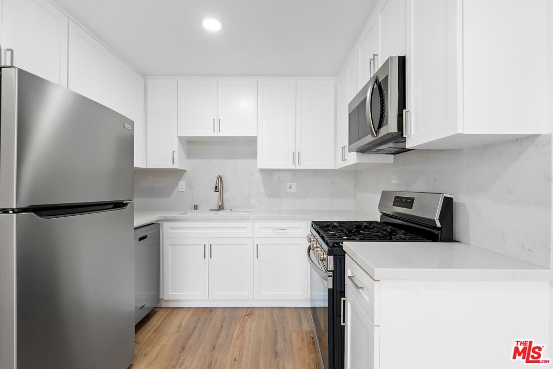 122 Buccaneer Street, Unit 1 Marina del Rey, CA 90292 - Photo 8 of 21 a kitchen with stainless steel appliances a refrigerator a sink and white cabinets