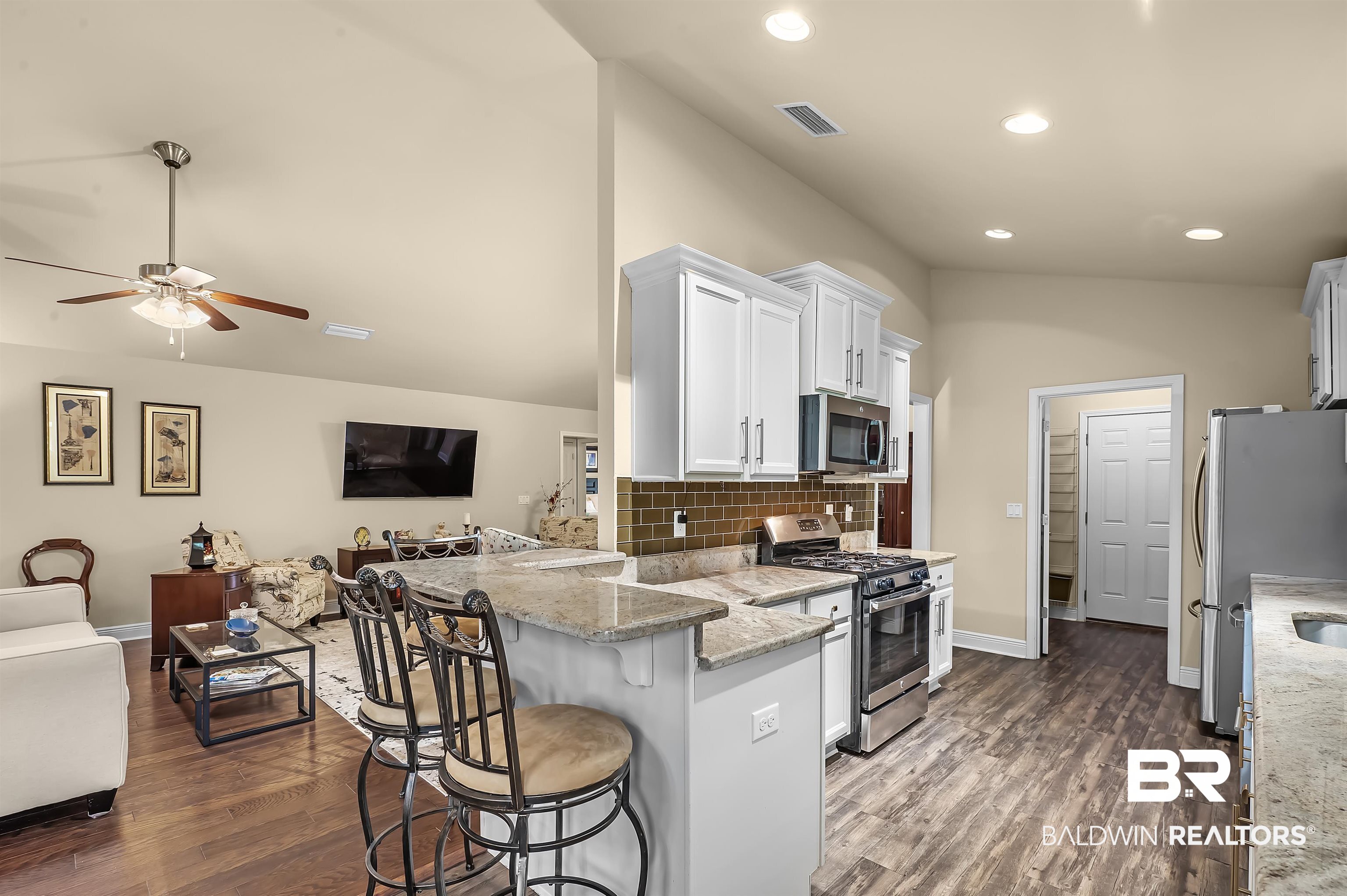 8896 Allay Lane Foley, AL 36535 - Photo 29 of 57 Kitchen featuring appliances with stainless steel finishes, kitchen peninsula, white cabinetry, light stone counters, and a breakfast bar
