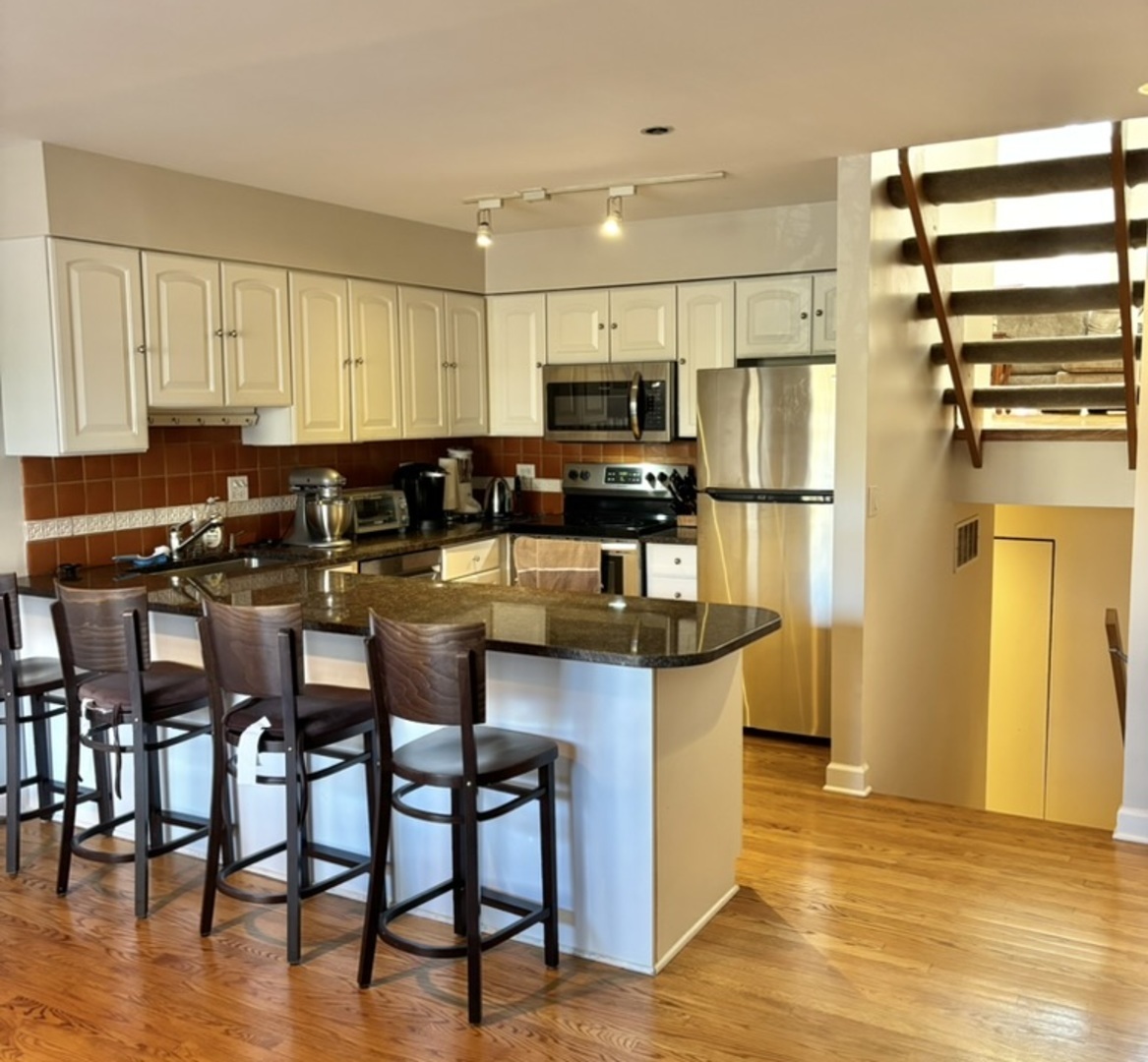 1229 Central Street, Unit A Evanston, IL 60201 - Photo 5 of 14 a kitchen with stainless steel appliances kitchen island granite countertop a table chairs and a refrigerator