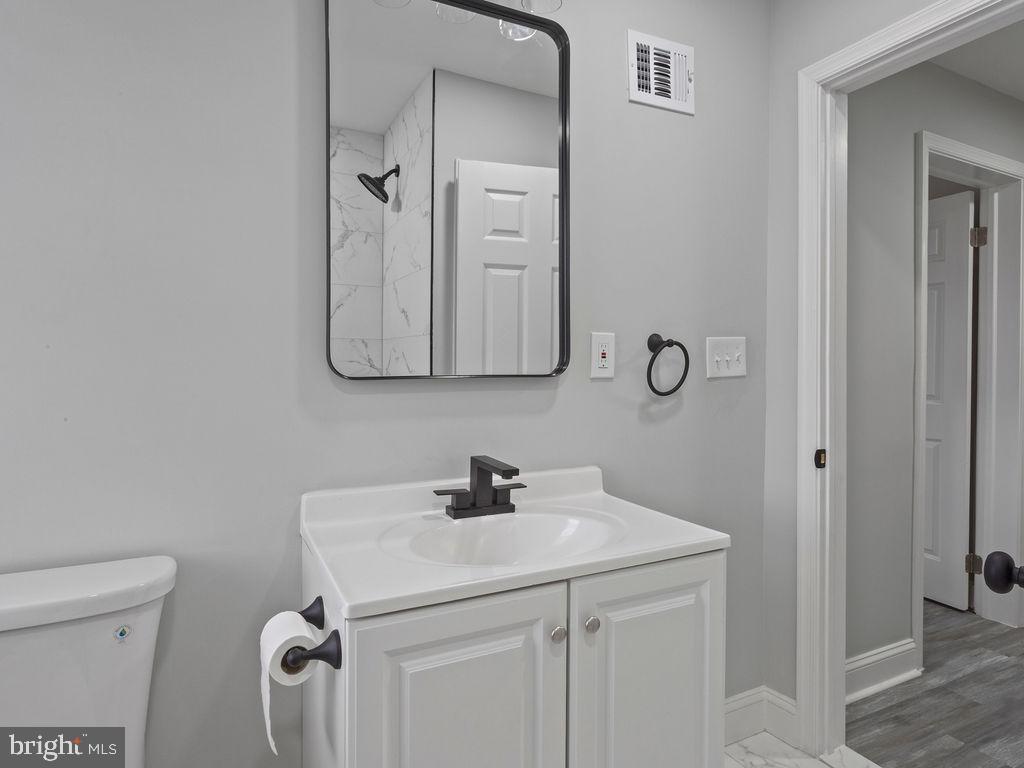 5716 Leith Walk Baltimore, MD 21239 - Photo 16 of 36 a bathroom with a sink a toilet and a mirror