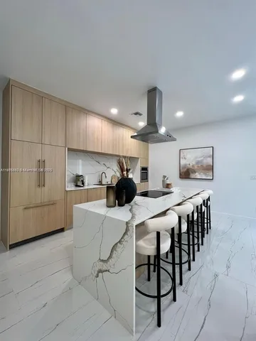 a kitchen with stainless steel appliances kitchen island granite countertop a table chairs sink and cabinets