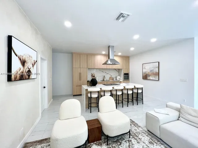a living room with furniture a table and kitchen view