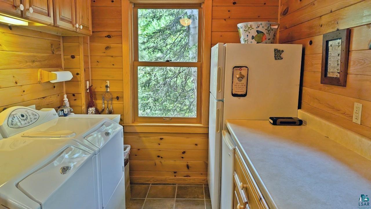 2357 Retreat Lodge Road Cook, MN 55723 - Photo 17 of 60 Laundry room with wooden walls, healthy amount of natural light, dark tile patterned floors, and washing machine and clothes dryer
