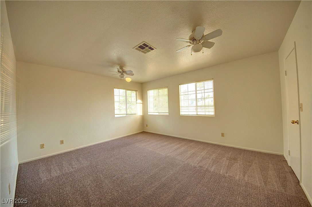 8332 Monico Valley Court Las Vegas, NV 89128 - Photo 6 of 14 Carpeted empty room featuring healthy amount of natural light, a textured ceiling, and ceiling fan