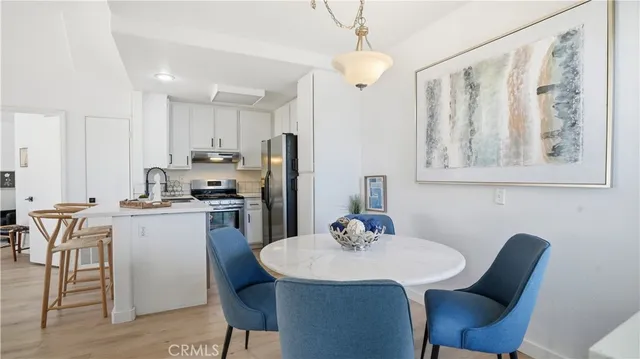 a kitchen with stainless steel appliances kitchen island granite countertop a dining table chairs and a refrigerator