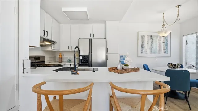 a kitchen with stainless steel appliances a sink a stove a table and chairs