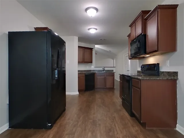 a kitchen with stainless steel appliances granite countertop a refrigerator a stove top oven a sink and dishwasher