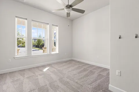 an empty room with windows and fan