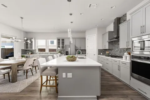 a kitchen with stainless steel appliances kitchen island granite countertop a stove a sink a dining table and chairs