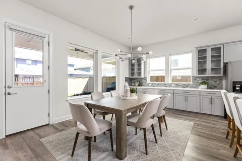 a kitchen with stainless steel appliances a dining table chairs and wooden floor