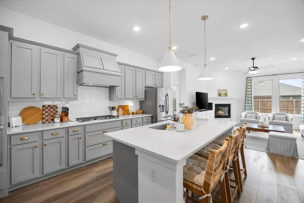 a view of a dining room and livingroom with furniture wooden floor a rug a fireplace and a chandelier