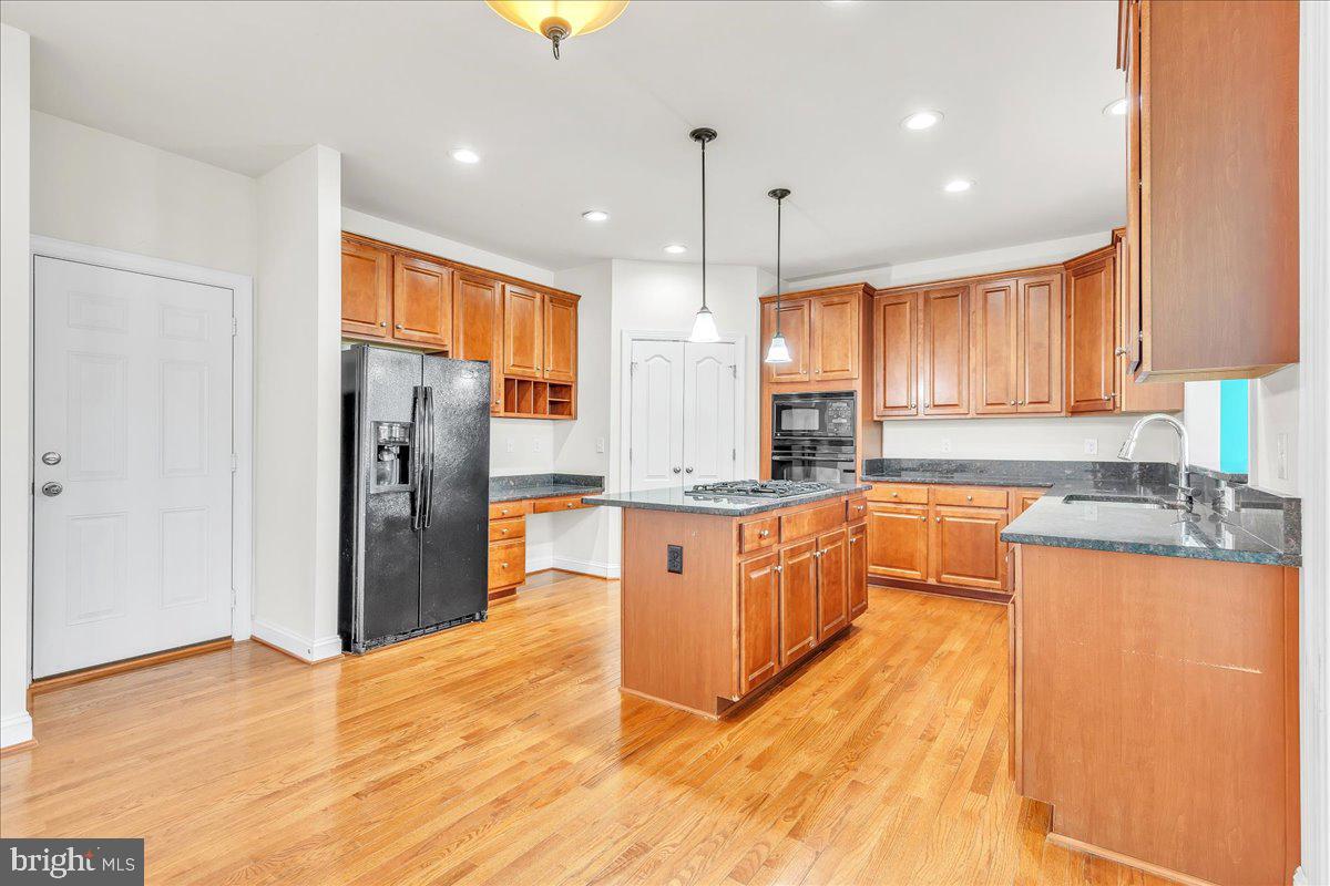 9588 Clover Hill Road Manassas, VA 20110 - Photo 13 of 32 a large kitchen with stainless steel appliances granite countertop a refrigerator a sink dishwasher a stove and white countertops with wooden floor