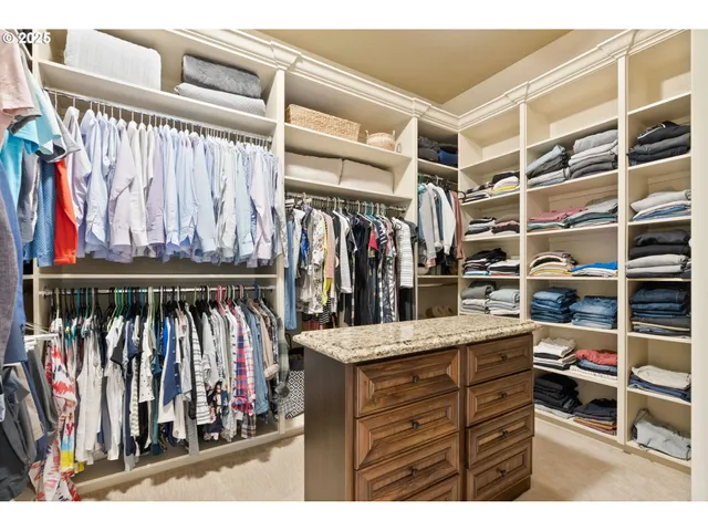a view of walk in closet with clothes and shoes