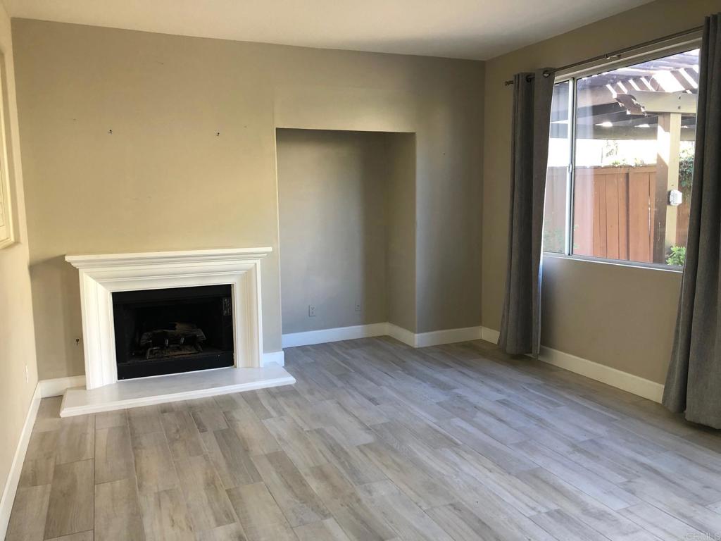 130 Venetia Way Oceanside, CA 92057 - Photo 4 of 19 an empty room with wooden floor fireplace and windows