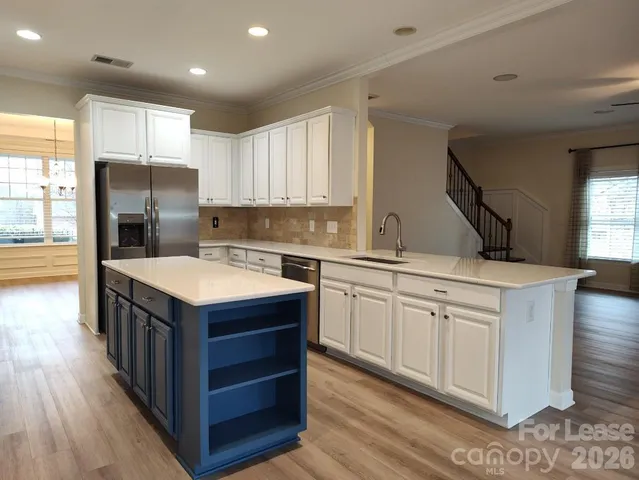 a kitchen with stainless steel appliances granite countertop a sink a stove a refrigerator and island with wooden floor