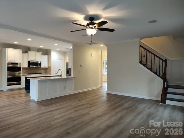 a view of an empty room with kitchen appliances and a ceiling fan