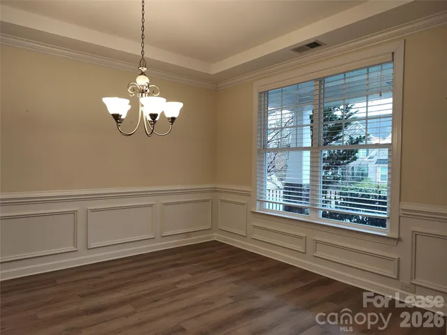 a view of a livingroom with a chandelier wooden floor and windows