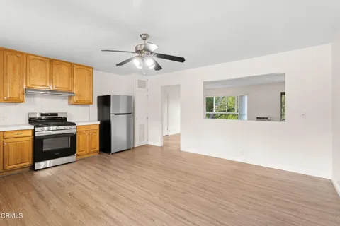 a kitchen with stainless steel appliances granite countertop a refrigerator a stove a sink and a microwave with wooden floor