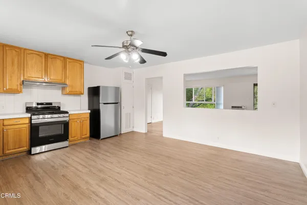 a kitchen with stainless steel appliances granite countertop a refrigerator a stove a sink and a microwave with wooden floor