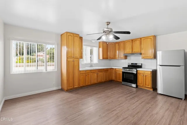 a kitchen with stainless steel appliances granite countertop a refrigerator a stove a sink dishwasher and a dining table with wooden floor